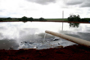Água saindo de um cano e caindo na água