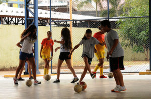 Crianças praticando futebol em quadra esportiva