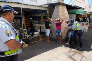 Imagem com policiais revistando possíveis suspeitos.
