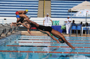 Atletas disputando prova na piscina. 