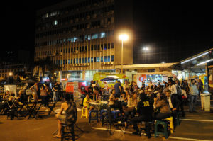 Imagem com pessoas sentadas comendo em um food truck no Setor Comercial Sul
