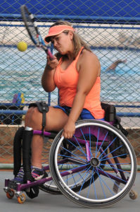 Mulher em cadeira de rodas jogando tênis. 