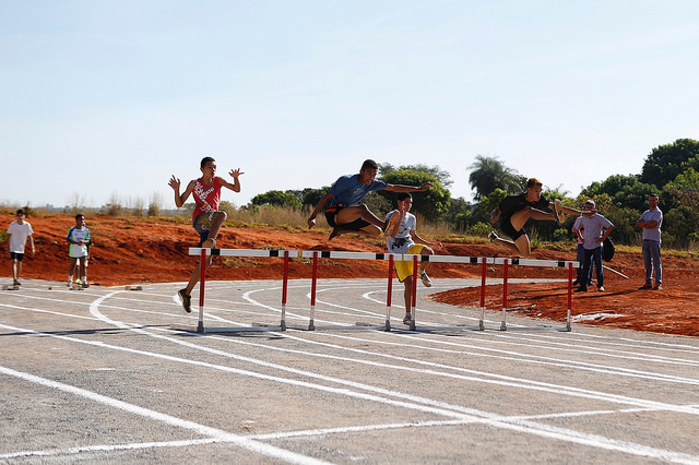 na foto, crianças saltam em corrida com obstáculos