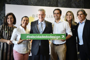 Na foto estão a oficial de projetos do setor de cultura da representação da Unesco no Brasil, Virgínia Casado, colaboradora do governo Márcia Rollemberg, governador de Brasília, Rodrigo Rollemberg, secretário adjunto do Turismo, Jaime Recena, subsecretária de Produtos e Políticas de Turismo, Caetana Franari, e secretário de Cultura, Guilherme Reis segurando uma placa que diz "bsbcidadedodesign"