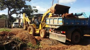 Trator retira entulhos e coloca na caçamba de caminhão