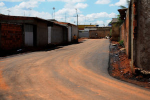 na imagem uma rua recé pavimentada no sol nascente