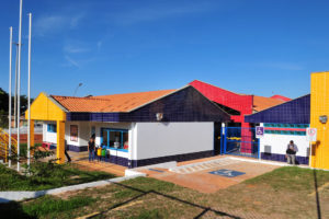 Imagem mostra entrada do prédio térreo, com vaga reservada para deficientes físicos