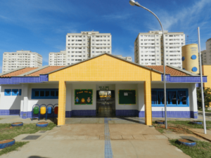Imagem da fachada da creche, um prédio de um andar pintado de amarelo e azul