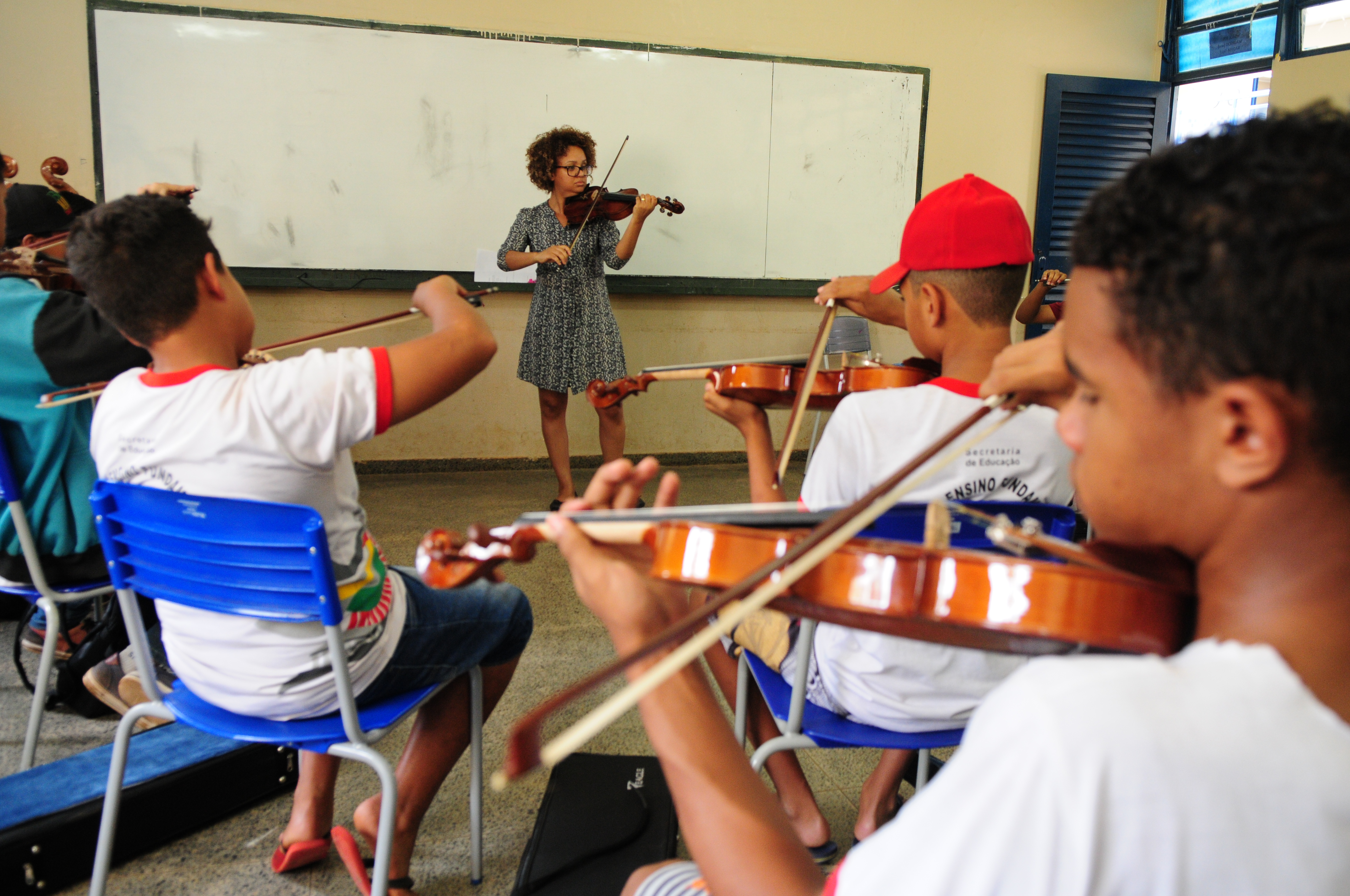 na foto, alunos tocam violino em uma aula de música