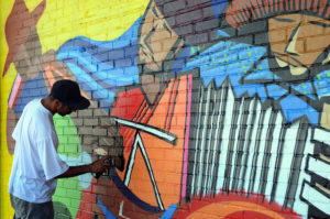 Jovem faz grafite colorido em muro