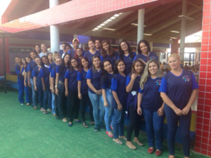 Professores uniformizados se juntam para tirar foto na frente da creche